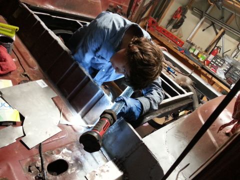 1984 Ford Bronco - Photo of a person welding a metal brace inside a vehicle body shell in a home workshop.