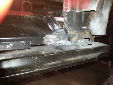 1984 Ford Bronco - Photo of a lower body panel and hinge pillar showing a bare-metal weld repair in a workshop.