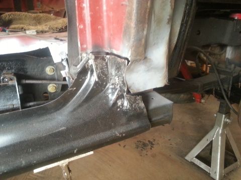 1984 Ford Bronco - Photo of a lower body and rocker area with weld repair, suspension visible, on a jack stand.