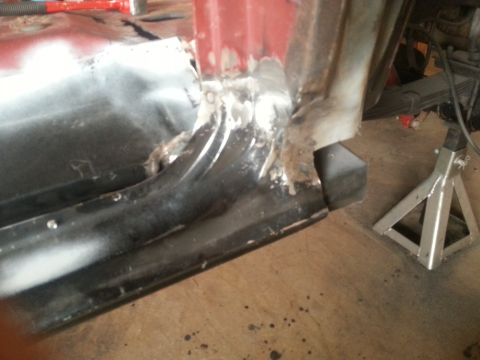 1984 Ford Bronco - Photo of a lower body corner with a welded patch and weld spatter, jack stand at right.