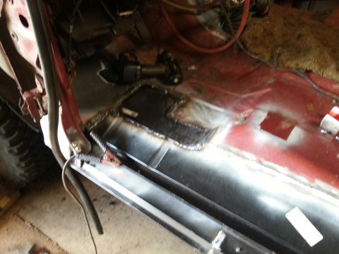 1984 Ford Bronco - Photo of a welded metal floor patch with continuous seam welds inside a red vehicle body shell.