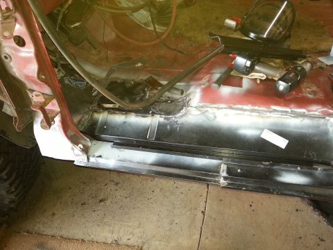 1984 Ford Bronco - Photo of new bare-metal floor and rocker panels welded into a vehicle body shell in a workshop.