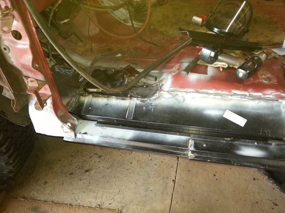 New bare-metal floor and rocker panels welded into a vehicle body shell in a workshop