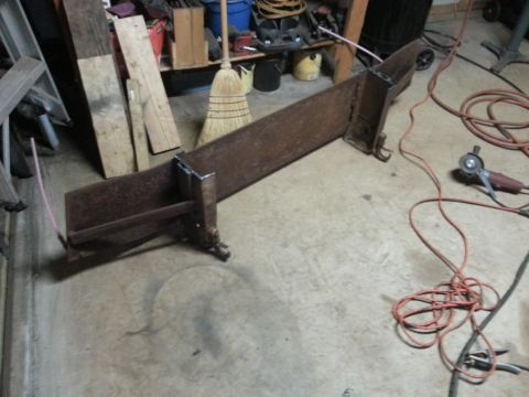 1984 Ford Bronco - Photo of a fabricated steel frame brace lying on a workshop floor, not a technical document.