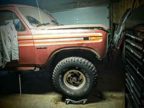 1984 Ford Bronco - Photo of a vintage Ford Bronco in a garage during restoration, not a technical document.