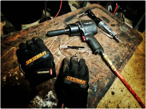 1984 Ford Bronco - Photo of an impact wrench and gloves on a workbench, not a technical document.