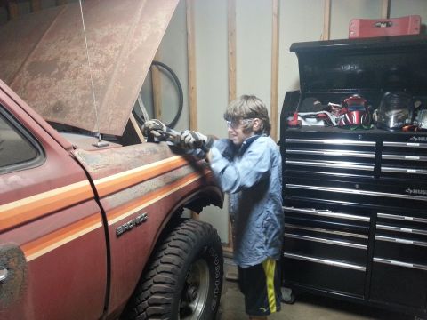 1984 Ford Bronco - Photo of a person servicing a vintage Ford truck in a garage, not a technical document.