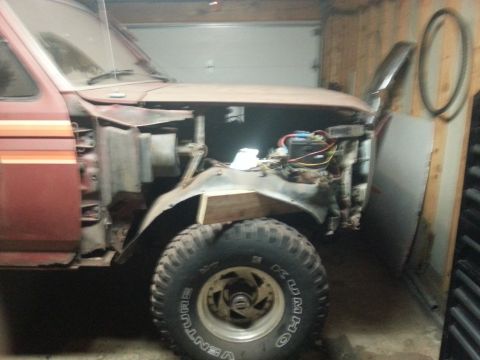 1984 Ford Bronco - Photo of a vintage Ford truck mid-restoration with front sheet metal removed, not a technical document.