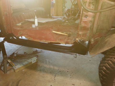 Stripped truck body on jack stands showing new rocker panel and floor