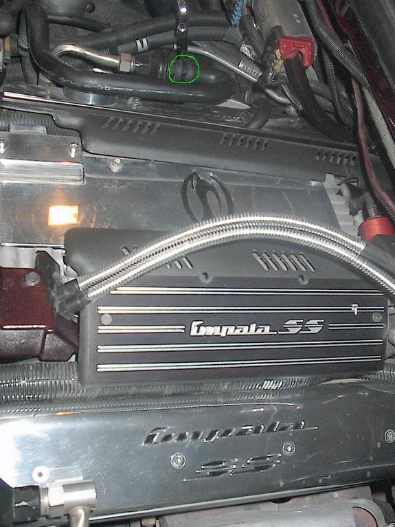 Engine bay with Impala SS badging on a black cover and a silver plate