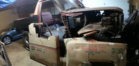 Project pickup truck in a garage with replacement fender parts boxes in front