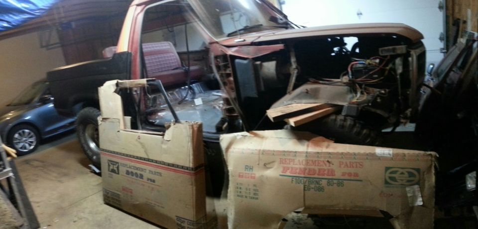Project pickup truck in a garage with replacement fender parts boxes in front