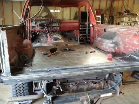 Stripped truck cab interior and bed floor with dash and wiring exposed