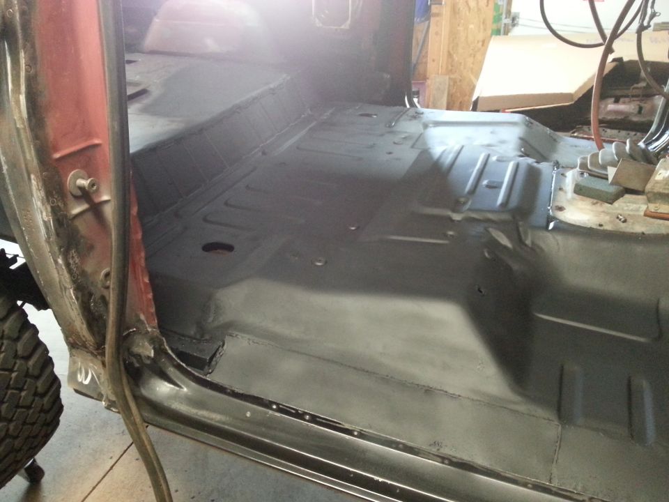 Primed truck cab floor pan and rocker viewed through the door opening