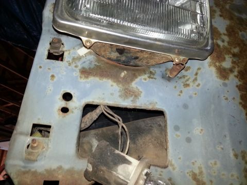 Rusty headlight bucket and front sheet metal panel of a vintage truck