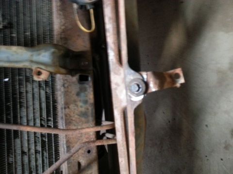 Radiator and rusty front-end bracket of a classic truck viewed from below
