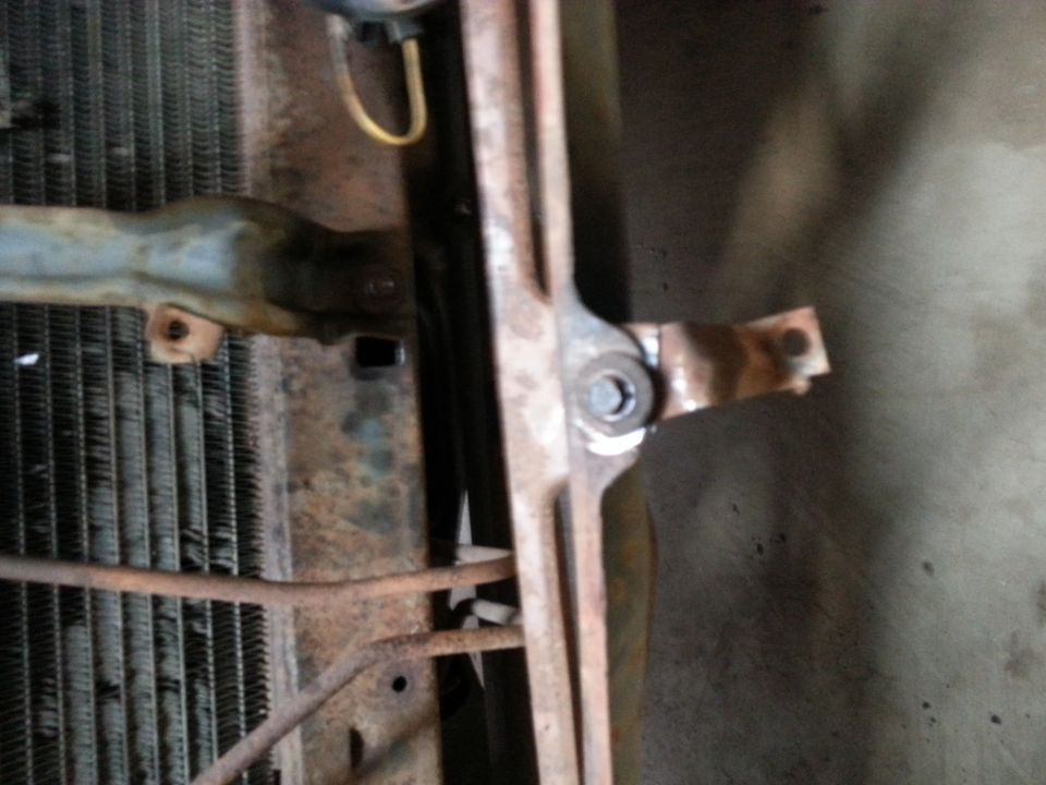 Radiator and rusty front-end bracket of a classic truck viewed from below