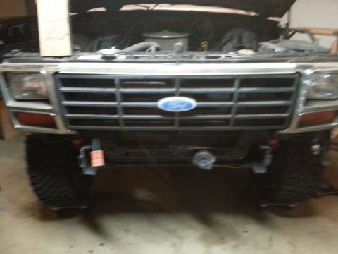 Front of a Ford truck with chrome grille and blue oval emblem, slightly blurry