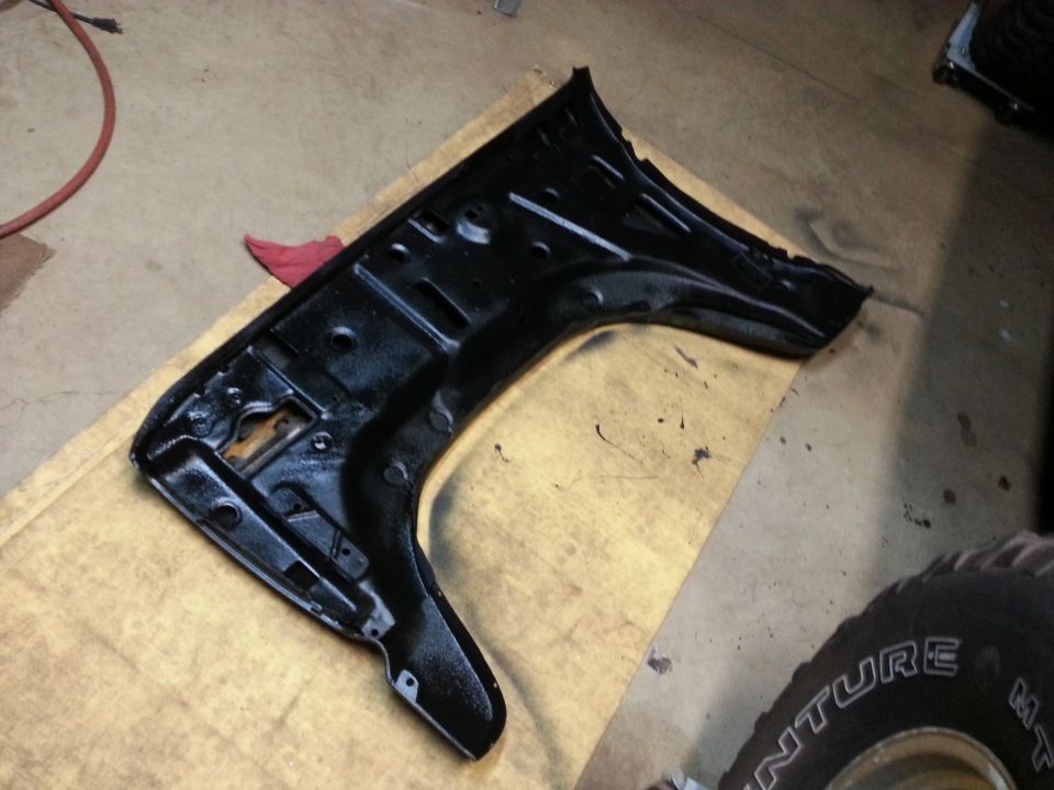 Black-painted sheet-metal fender support panel on cardboard