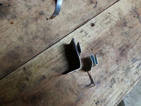 Small metal brackets resting on a wooden workbench
