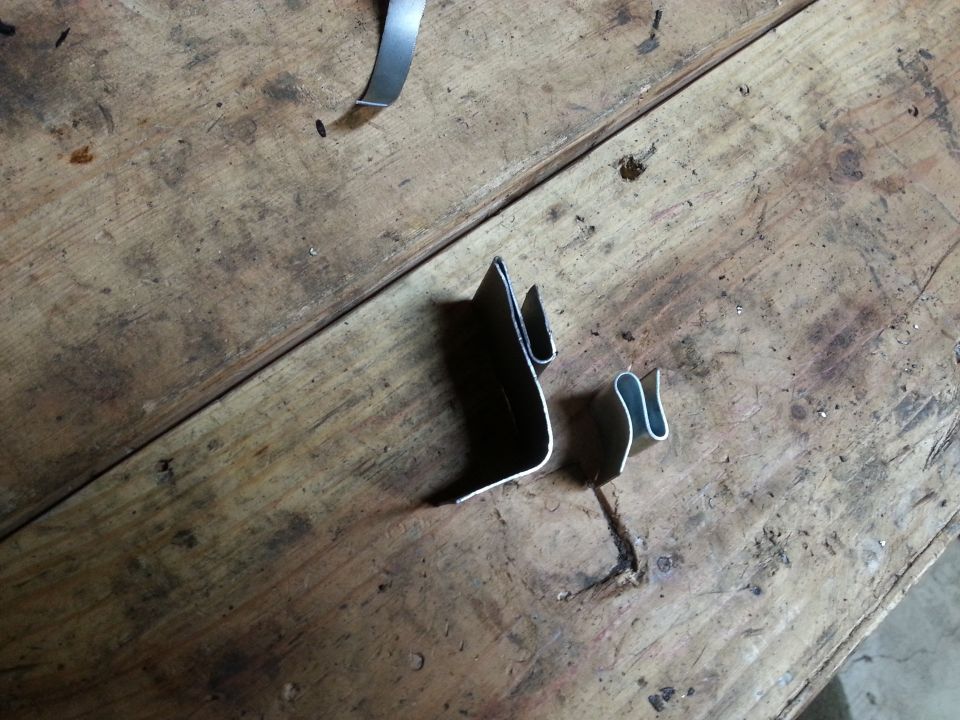 Small metal brackets resting on a wooden workbench