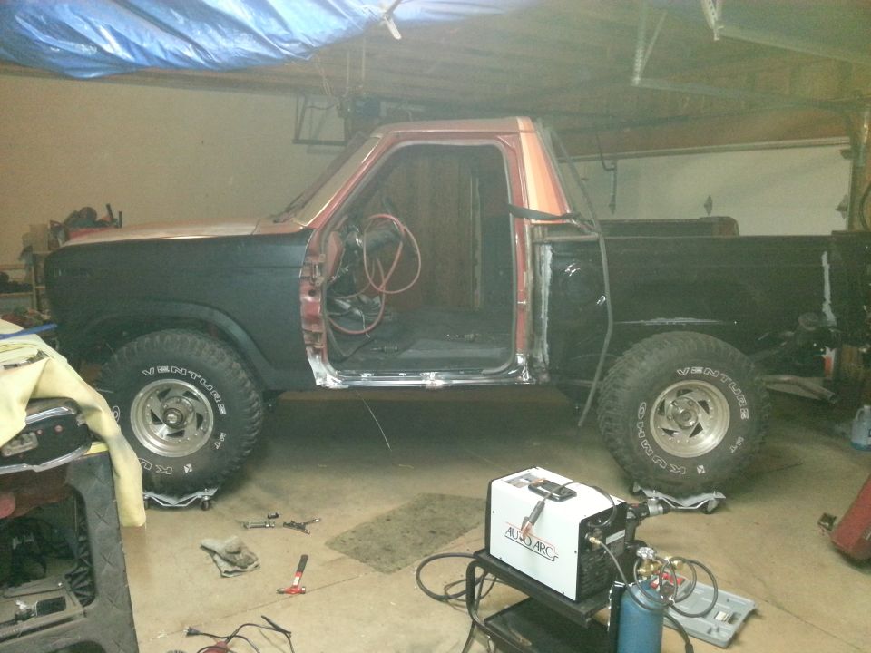 Truck on jack stands with welder during bodywork