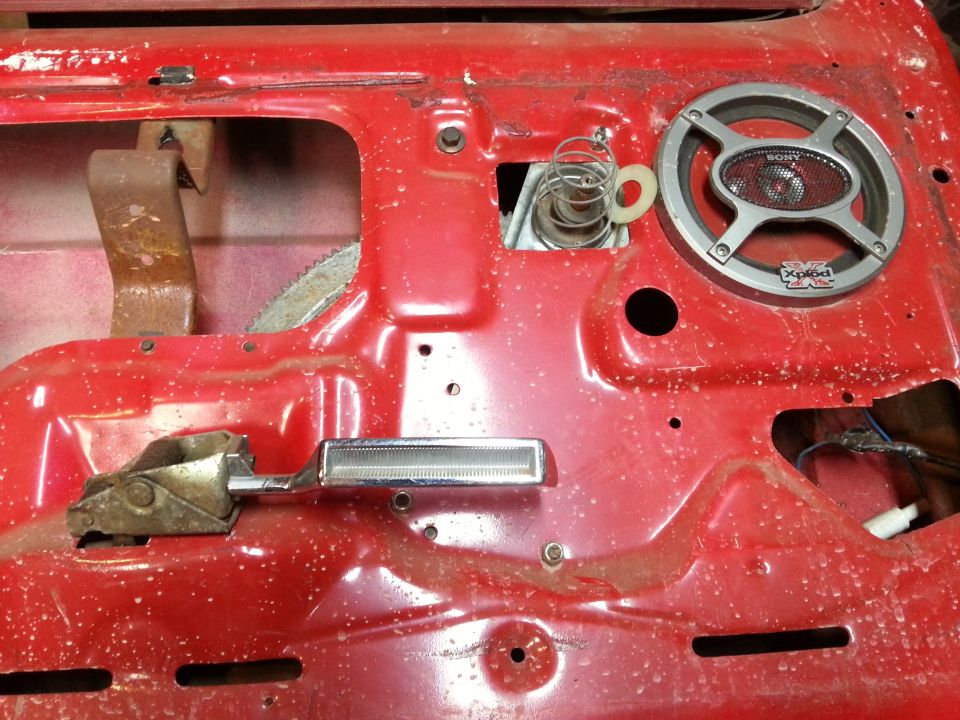 Photo of a red vehicle door shell interior with a Sony speaker and latch parts