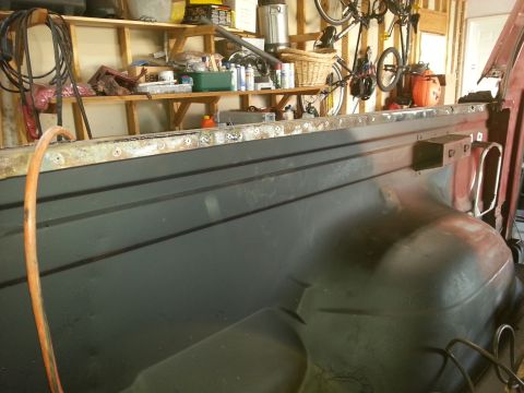 Photo of a primered truck bed side in a cluttered garage workshop
