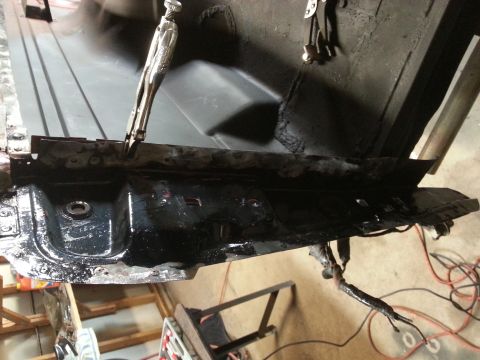 Photo of a wet black-coated vehicle floor or frame section during restoration