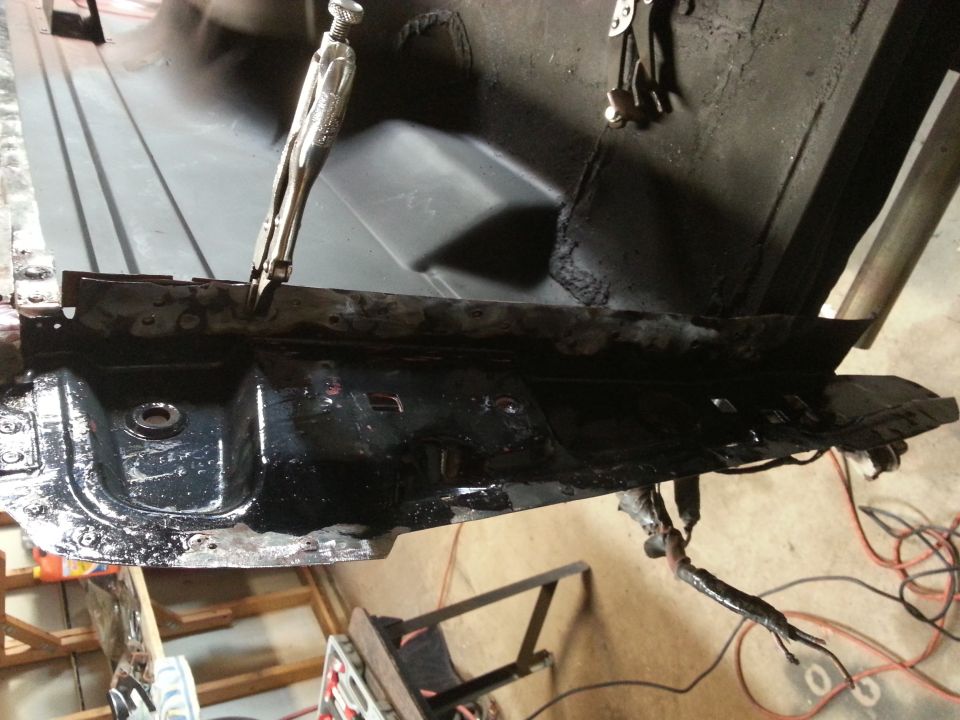 Photo of a wet black-coated vehicle floor or frame section during restoration