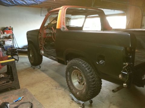 Photo of a black-painted Ford Bronco body on jack stands in a garage