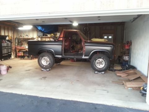 Photo of a primered Ford truck on dollies inside a home garage