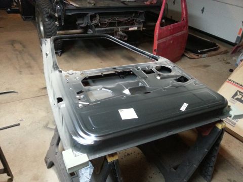 Photo of a bare-metal vehicle door shell on a stand in a garage