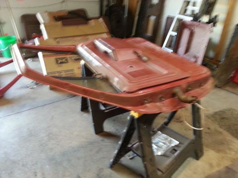 Photo of a red vehicle door shell with armrest on sawhorses in a garage