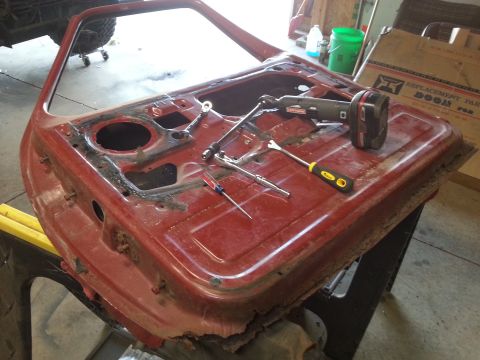 Photo of a red vehicle door interior with tools laid out during repair
