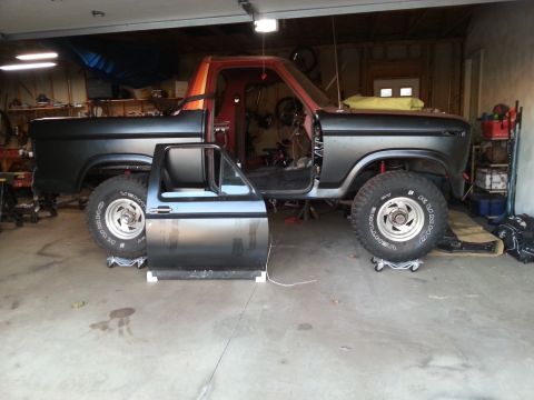 Photo of a Ford truck body and removed door on dollies in a garage