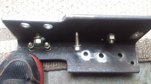 Steel mounting bracket with bolts and nuts laid on the ground