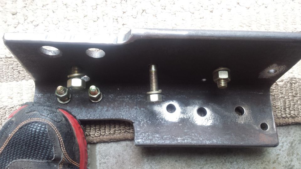 Steel mounting bracket with bolts and nuts laid on the ground