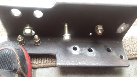 Steel mounting bracket with bolt holes and hardware on pavement