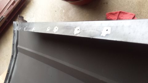 Edge of a sheet-metal body panel with mounting clips in a garage