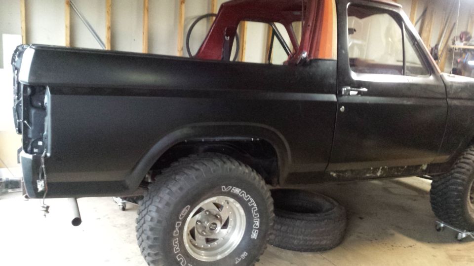 Side view of a lifted black Ford Bronco in a garage
