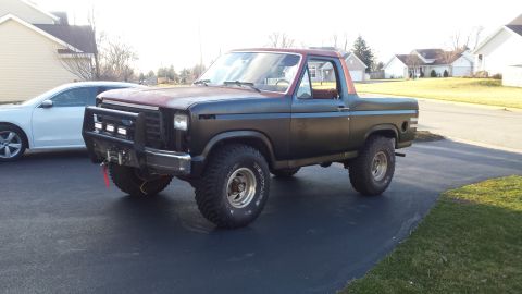 Front three-quarter view of a lifted classic Ford Bronco in a driveway