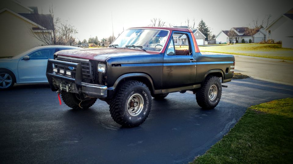 Lifted classic Ford Bronco parked in a driveway on a sunny day