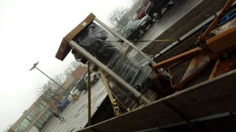 Tilted view of crated equipment being loaded outdoors on a wet day