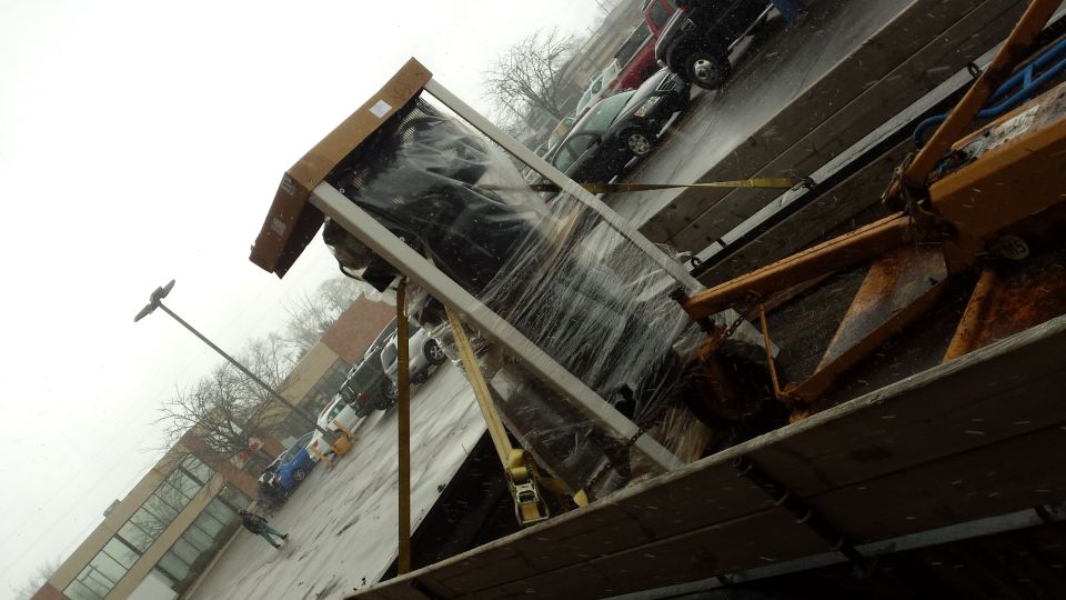 Tilted view of crated equipment being loaded outdoors on a wet day