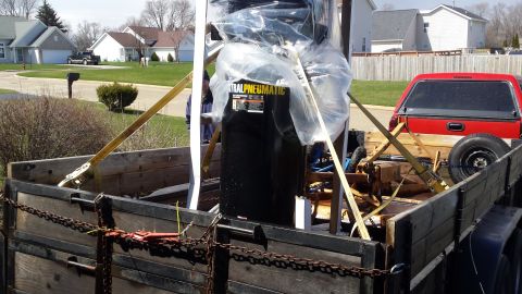 Wrapped pneumatic equipment strapped on a wooden trailer bed