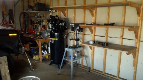Garage workshop with air compressor, drill press, and shelving
