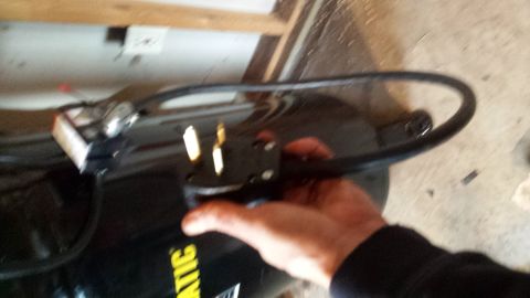 Hand holding an air compressor power cord and plug