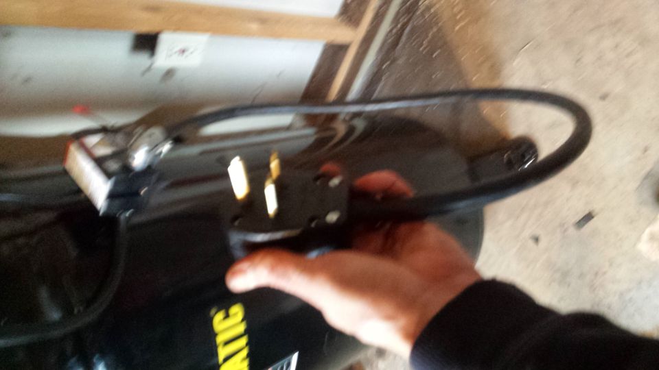 Hand holding an air compressor power cord and plug
