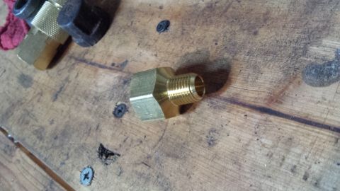 Brass pipe fitting on a wooden workbench